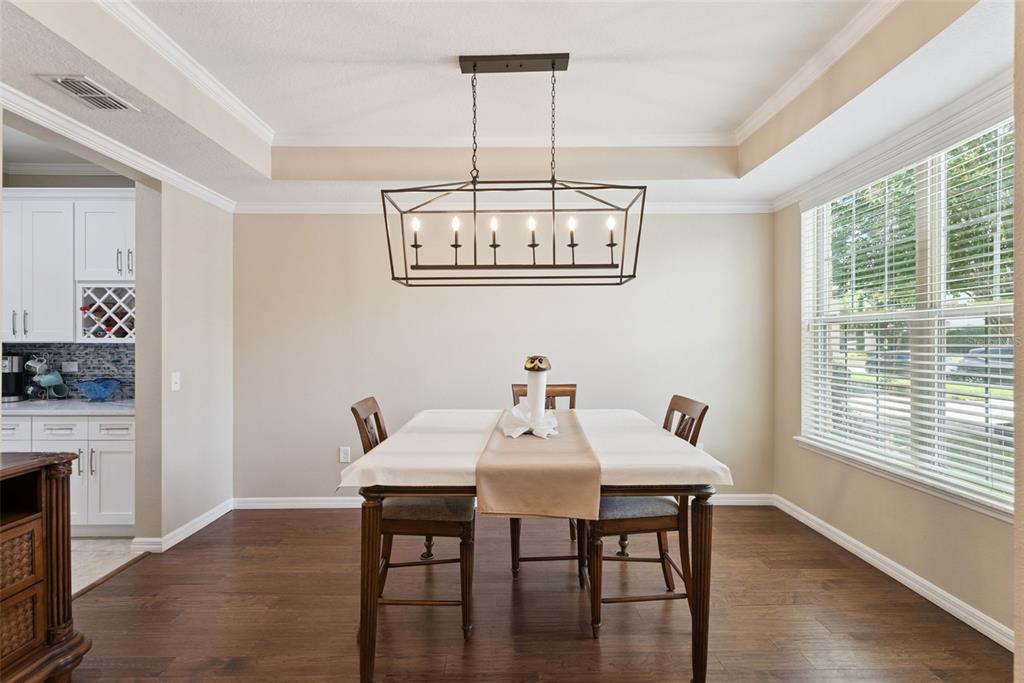 A dining room features a rectangular chandelier, a table with a runner, and hardwood floors — 8701 IRON MOUNTAIN TRAIL, WINDERMERE, FL
