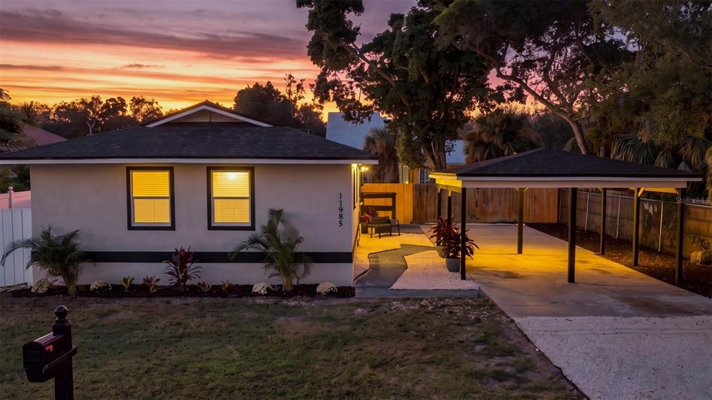 A single-story house with a carport and a sunset sky in the background — 11985 MURRAY AVENUE, SEMINOLE, FL