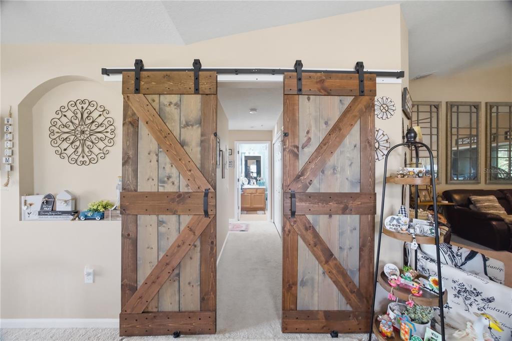 Two rustic wooden barn doors hang on a black metal track in a carpeted room — 2111 RIVER TURIA CIRCLE, RIVERVIEW, FL