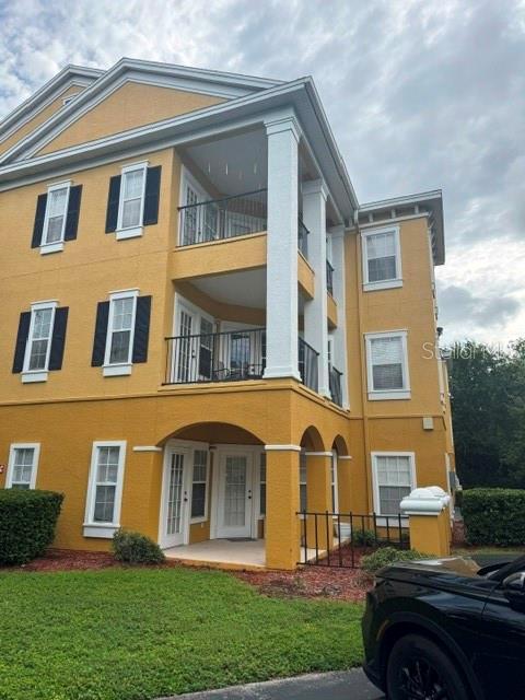 The exterior of a multi-story yellow apartment building features white columns and balconies — 3615 CONROY ROAD UNIT 627, ORLANDO, FL