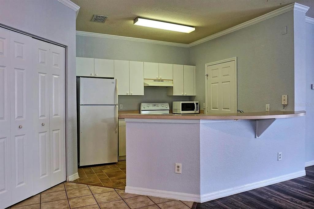 A kitchen features white cabinets, white appliances, a breakfast bar, and tile flooring — 3615 CONROY ROAD UNIT 627, ORLANDO, FL