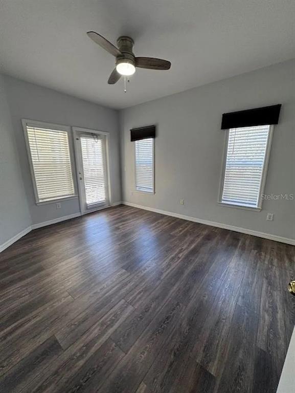 An empty room features wood-look flooring, light gray walls, a ceiling fan, and three windows — 3615 CONROY ROAD UNIT 627, ORLANDO, FL