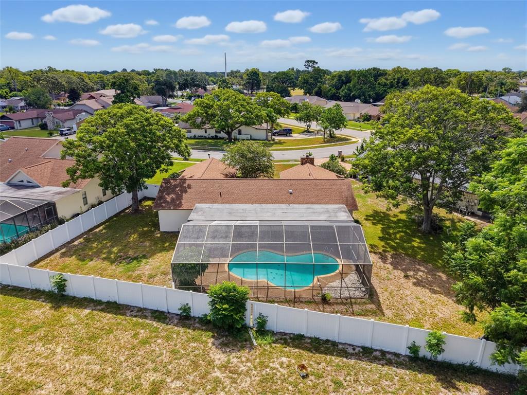 An aerial view of a house with a screened-in pool and a white vinyl fence — 13241 HILLWOOD CIRCLE, HUDSON, FL