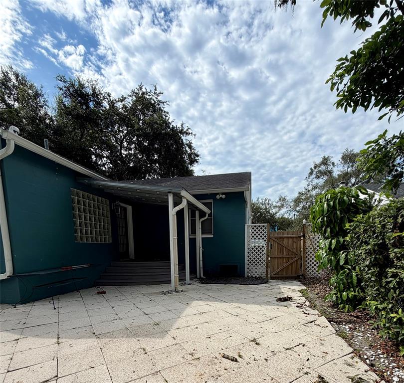 A teal house exterior features a covered patio, a glass block window, and a wooden gate — 471 HOLT AVENUE, WINTER PARK, FL