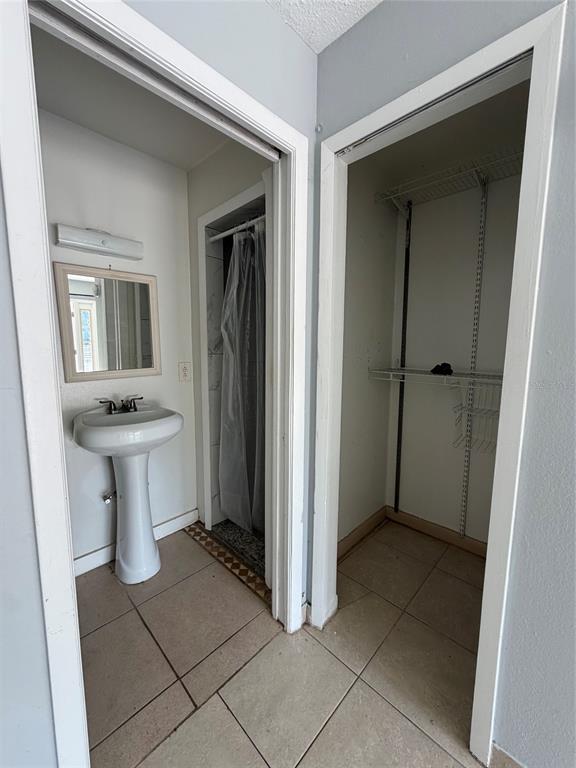 A bathroom with a pedestal sink and mirror next to an open closet with shelving — 471 HOLT AVENUE, WINTER PARK, FL