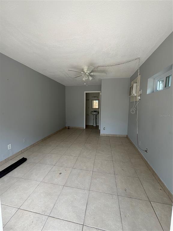 An empty room with light gray walls, tile flooring, a ceiling fan, and a doorway — 471 HOLT AVENUE, WINTER PARK, FL