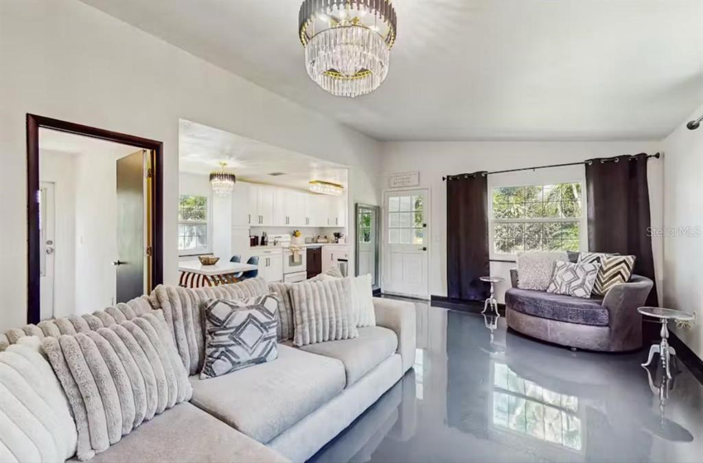 A living room with a grey sectional sofa, glossy floors, and a crystal chandelier — 4210 OLIVE AVENUE, SARASOTA, FL