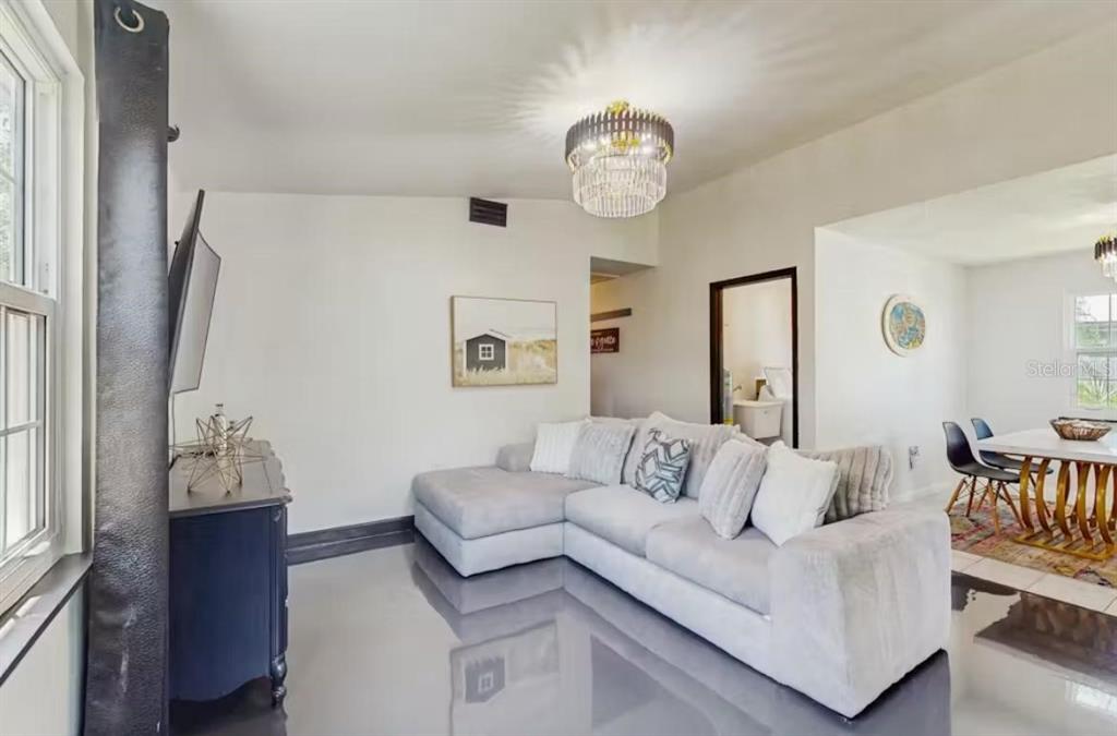 A living room features a grey sectional sofa, glossy dark floors, and a crystal chandelier — 4210 OLIVE AVENUE, SARASOTA, FL
