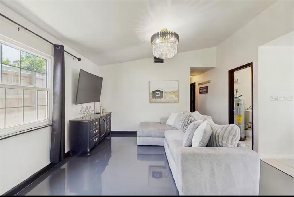 A living room features a grey sectional sofa, a dark dresser, and a crystal chandelier — 4210 OLIVE AVENUE, SARASOTA, FL