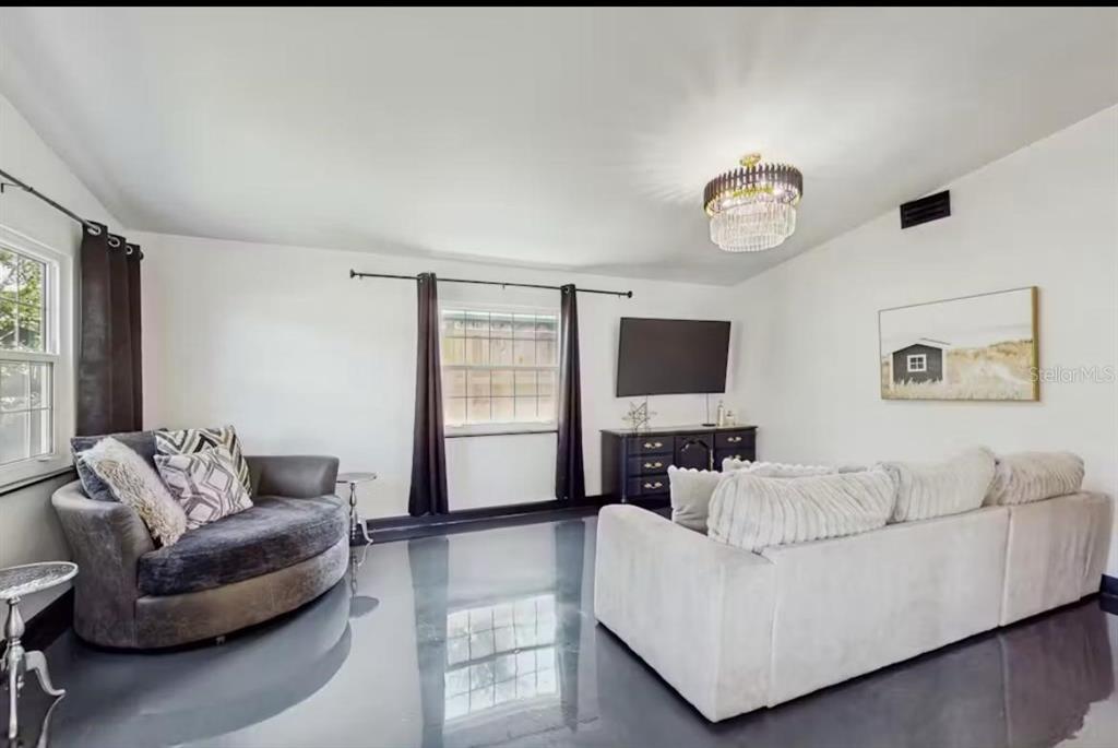 A living room with a grey circular chair, white sofa, and dark glossy flooring — 4210 OLIVE AVENUE, SARASOTA, FL