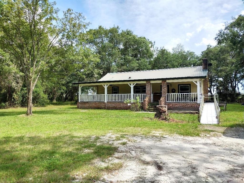 A single-story house with a metal roof, brick foundation, and a wide front porch — 9983 W HIGHWAY 100, BUNNELL, FL