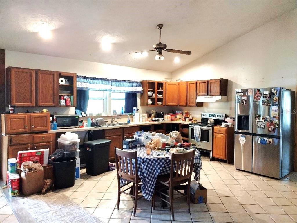 A kitchen with wood cabinets, stainless steel appliances, and a central dining table — 9983 W HIGHWAY 100, BUNNELL, FL
