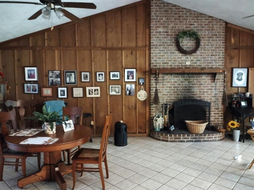 A dining area with wood paneling, a brick fireplace, and tile flooring — 9983 W HIGHWAY 100, BUNNELL, FL