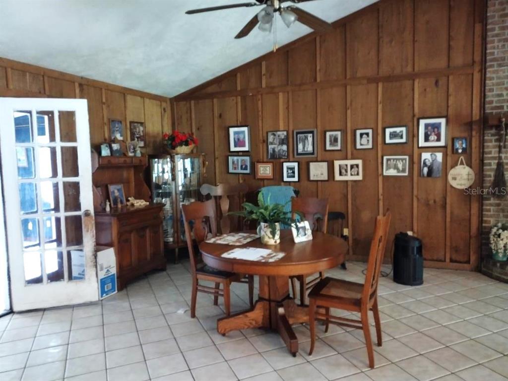 A dining area features wood-paneled walls, a round wooden table, and tiled flooring — 9983 W HIGHWAY 100, BUNNELL, FL