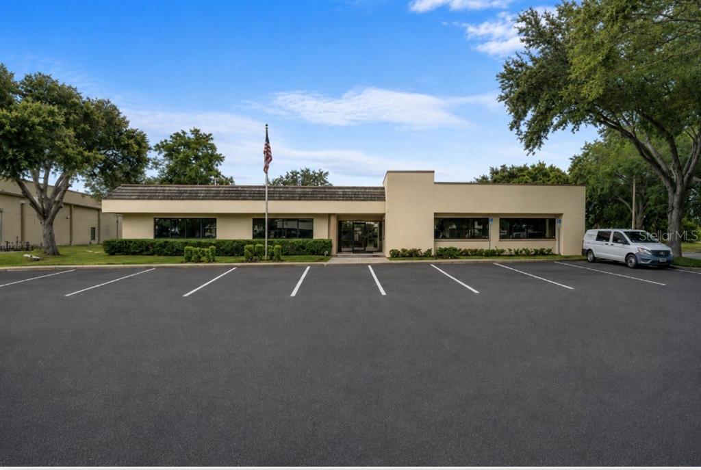 A single-story commercial building with a parking lot, flag pole, and surrounding trees — 2453 ORLANDO CENTRAL PARKWAY, ORLANDO, FL