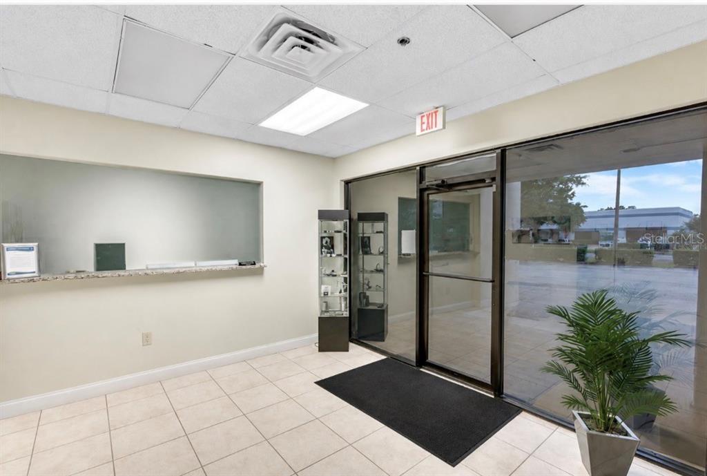 A commercial office lobby features a reception window, glass entrance doors, and tiled flooring — 2453 ORLANDO CENTRAL PARKWAY, ORLANDO, FL