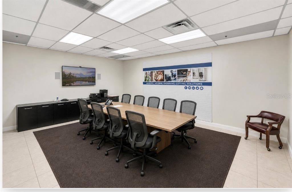 A conference room features a long wooden table, rolling office chairs, and a wall mural — 2453 ORLANDO CENTRAL PARKWAY, ORLANDO, FL