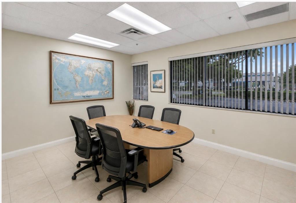 A conference room features a light wood oval table, black chairs, and a world map — 2453 ORLANDO CENTRAL PARKWAY, ORLANDO, FL