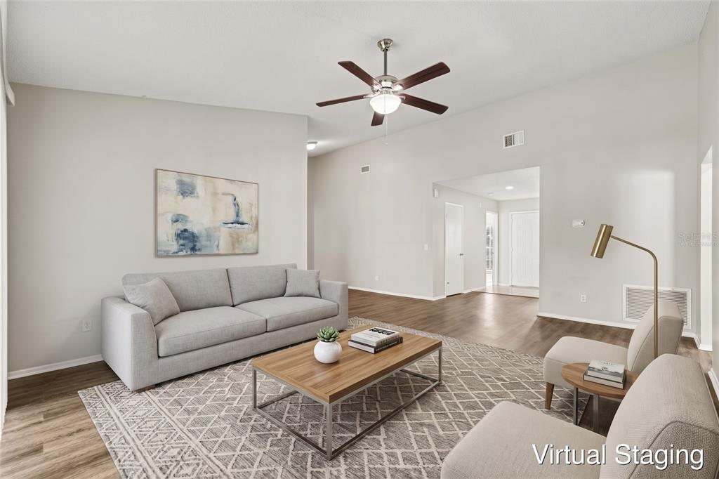 An empty living room with wood-look flooring, a ceiling fan, and sliding glass patio doors — 8304 NATCHEZ STREET, TAMPA, FL