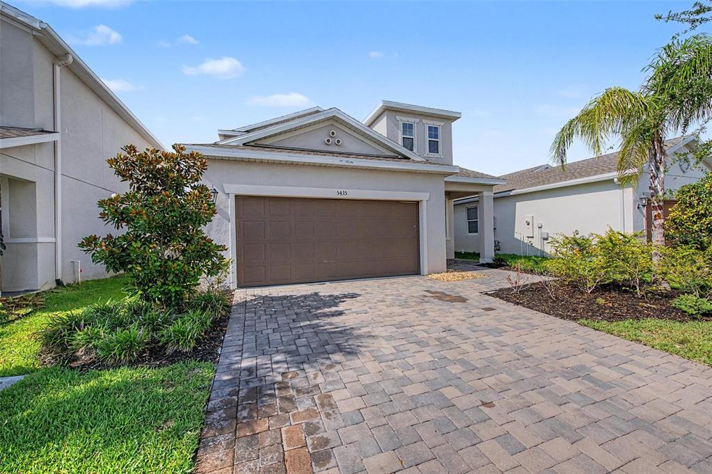 A single-story house features a brown garage door, a paved driveway, and a small palm tree — 5435 BUNGALOW GROVE COURT, PALMETTO, FL