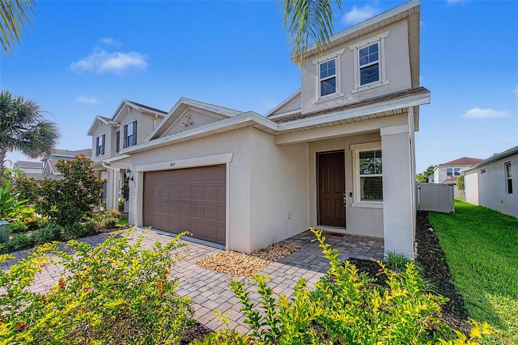 A two-story suburban house with a brown garage door, paved driveway, and a small front porch — 5435 BUNGALOW GROVE COURT, PALMETTO, FL