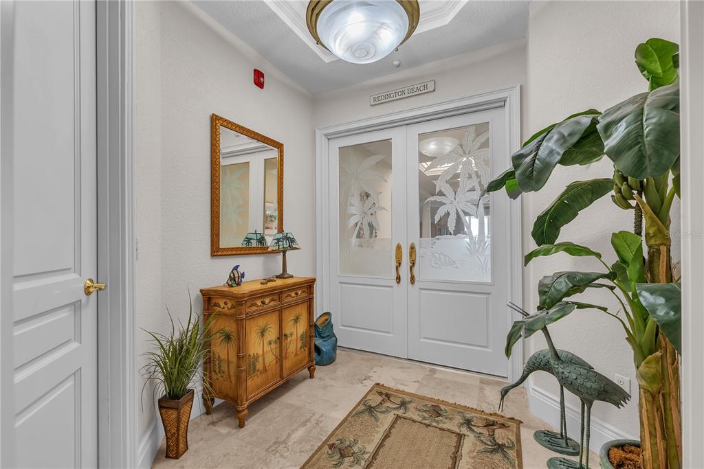 An entryway features a light-colored tile floor, a wooden cabinet, and double glass-paneled doors — 16300 GULF BOULEVARD UNIT 500A, REDINGTON BEACH, FL