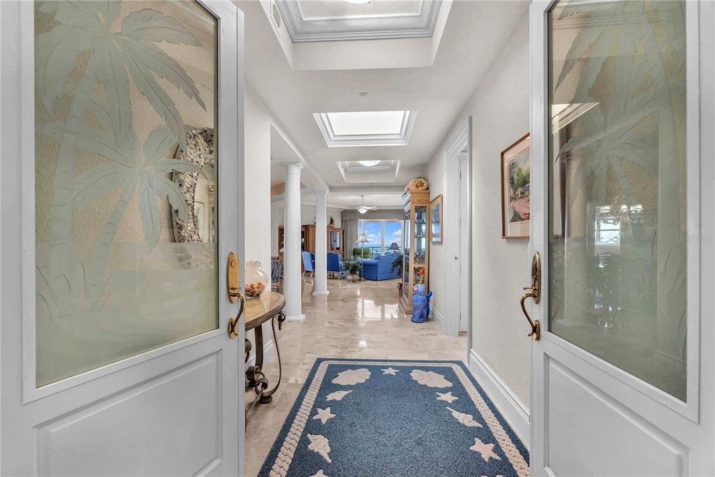 A foyer with glass-paneled doors leads into a bright living area with marble floors — 16300 GULF BOULEVARD UNIT 500A, REDINGTON BEACH, FL