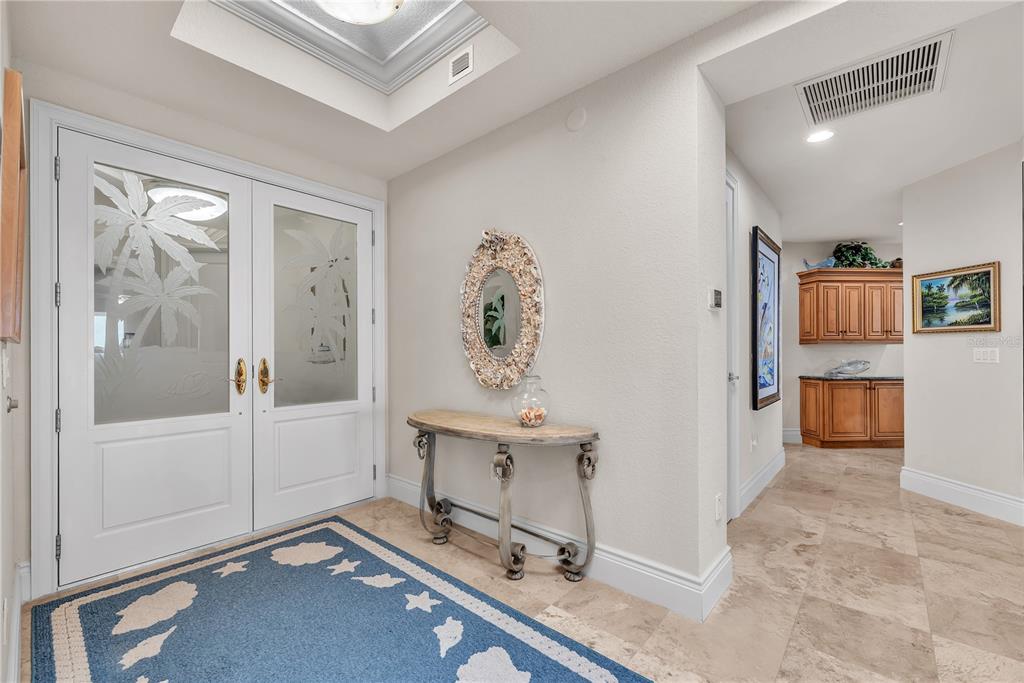 An entryway features double glass doors, a console table with a mirror, and tile flooring — 16300 GULF BOULEVARD UNIT 500A, REDINGTON BEACH, FL