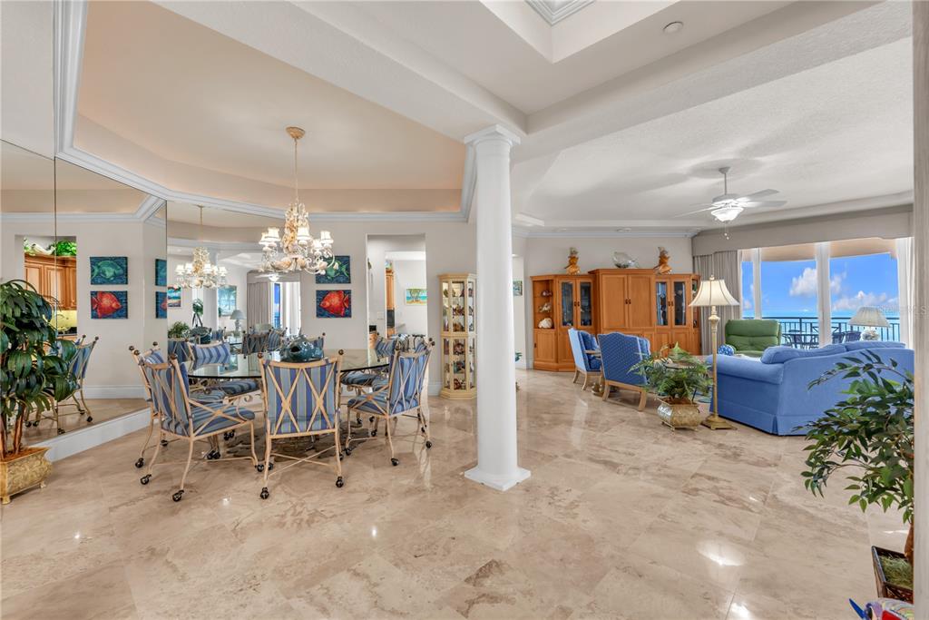 A spacious open-concept living and dining area with marble floors, a white pillar, and ocean views — 16300 GULF BOULEVARD UNIT 500A, REDINGTON BEACH, FL