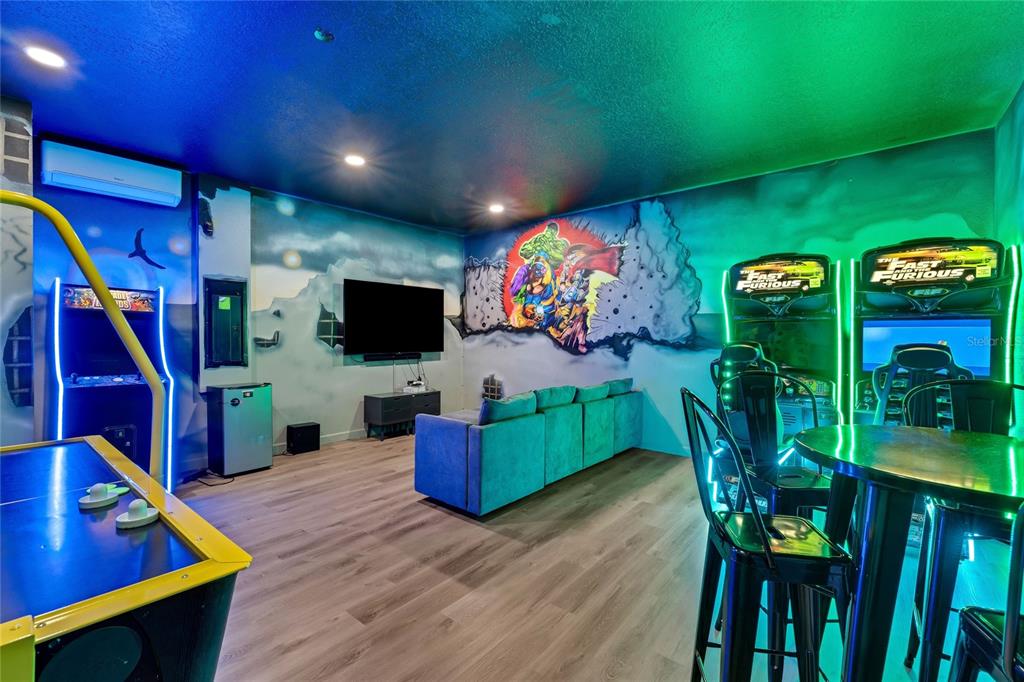 A game room features arcade machines, an air hockey table, a television, and muraled walls — 1577 PLUNKER DRIVE, DAVENPORT, FL