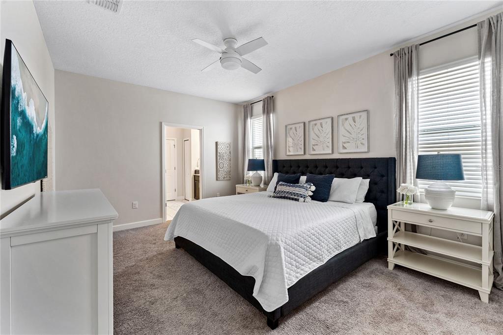 A bedroom features a dark tufted bed, white furniture, and a ceiling fan — 1577 PLUNKER DRIVE, DAVENPORT, FL