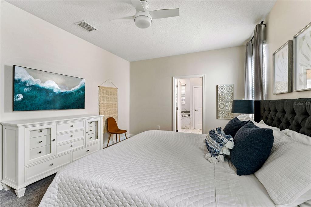 A bedroom features a white dresser, a tufted headboard, and a ceiling fan — 1577 PLUNKER DRIVE, DAVENPORT, FL