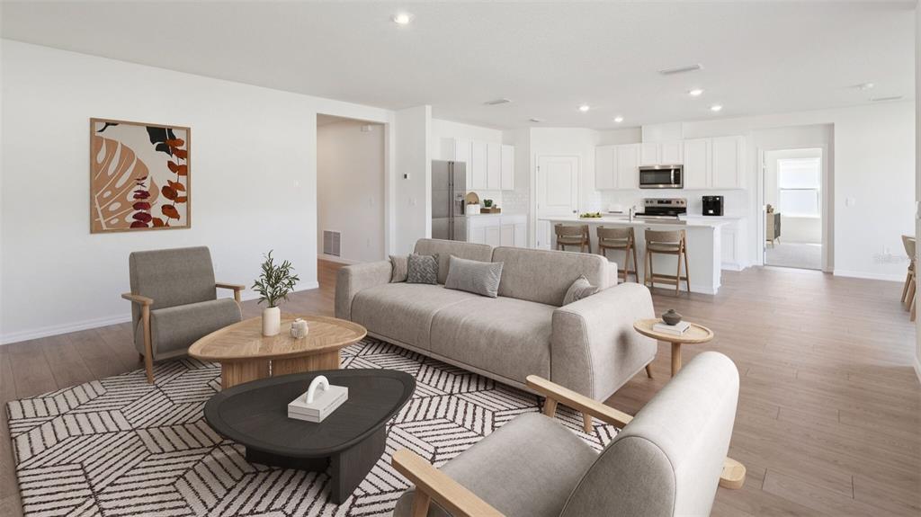 This open-concept living room features a sofa, armchairs, coffee tables, and an adjacent kitchen — 5416 SW 55TH TERRACE, GAINESVILLE, FL