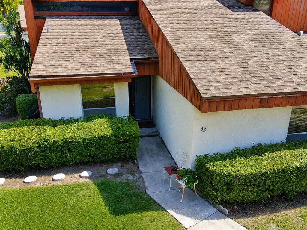 An exterior view of a house entrance with a walkway, landscaping, and house number 38 — 2054 SUNSET POINT ROAD UNIT 38, CLEARWATER, FL