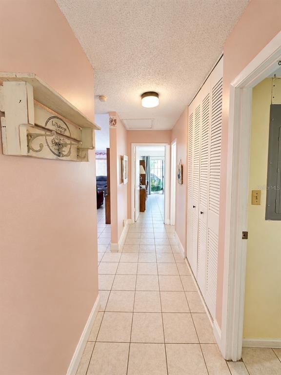 A hallway with light-colored tile flooring, pink walls, and white louvered closet doors — 2054 SUNSET POINT ROAD UNIT 38, CLEARWATER, FL