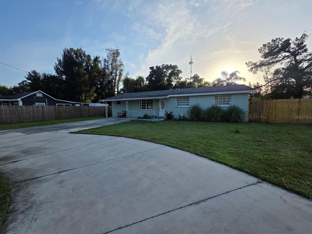 A single-story house with a light green exterior, a concrete driveway, and a wooden fence — 3412 16TH STREET E, BRADENTON, FL