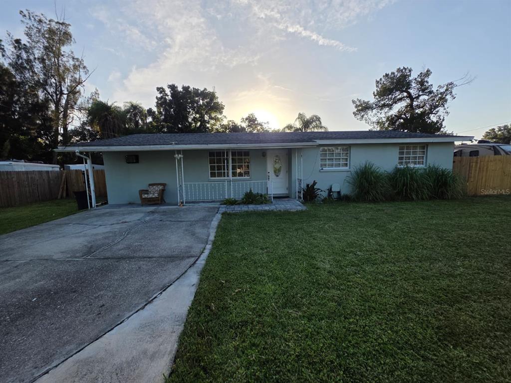 A single-story house with a light green exterior, a concrete driveway, and a front lawn — 3412 16TH STREET E, BRADENTON, FL