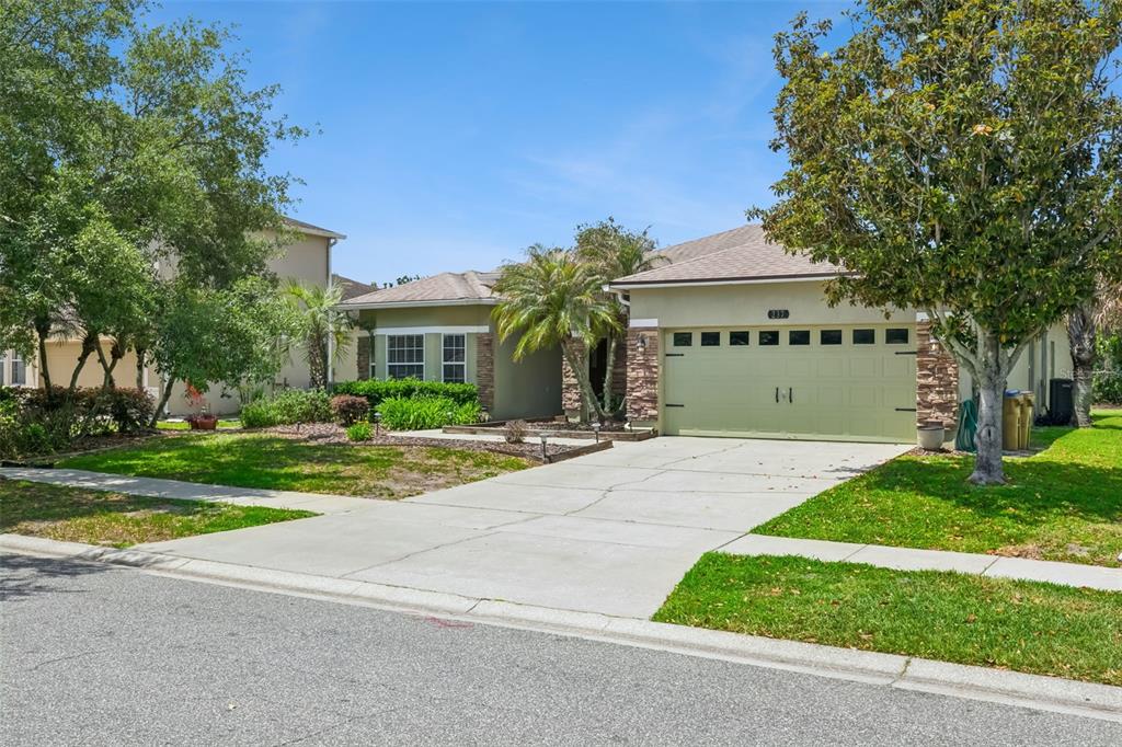 A single-story house with a beige exterior, stone accents, a two-car garage, and a driveway — 237 STRATHMORE CIRCLE, KISSIMMEE, FL