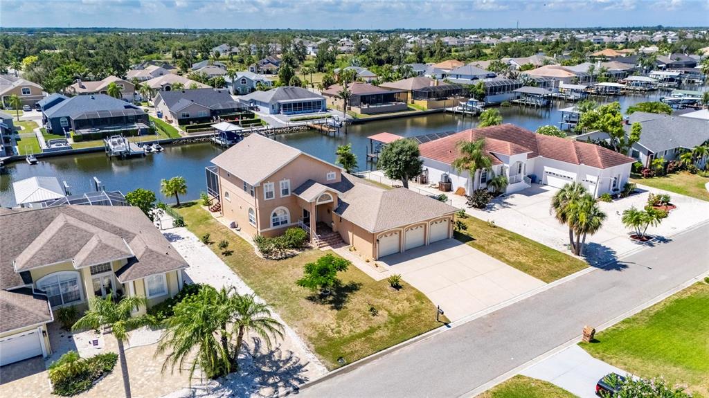 An aerial view shows a tan suburban house with a three-car garage near a canal — 830 GOLF ISLAND DRIVE, APOLLO BEACH, FL