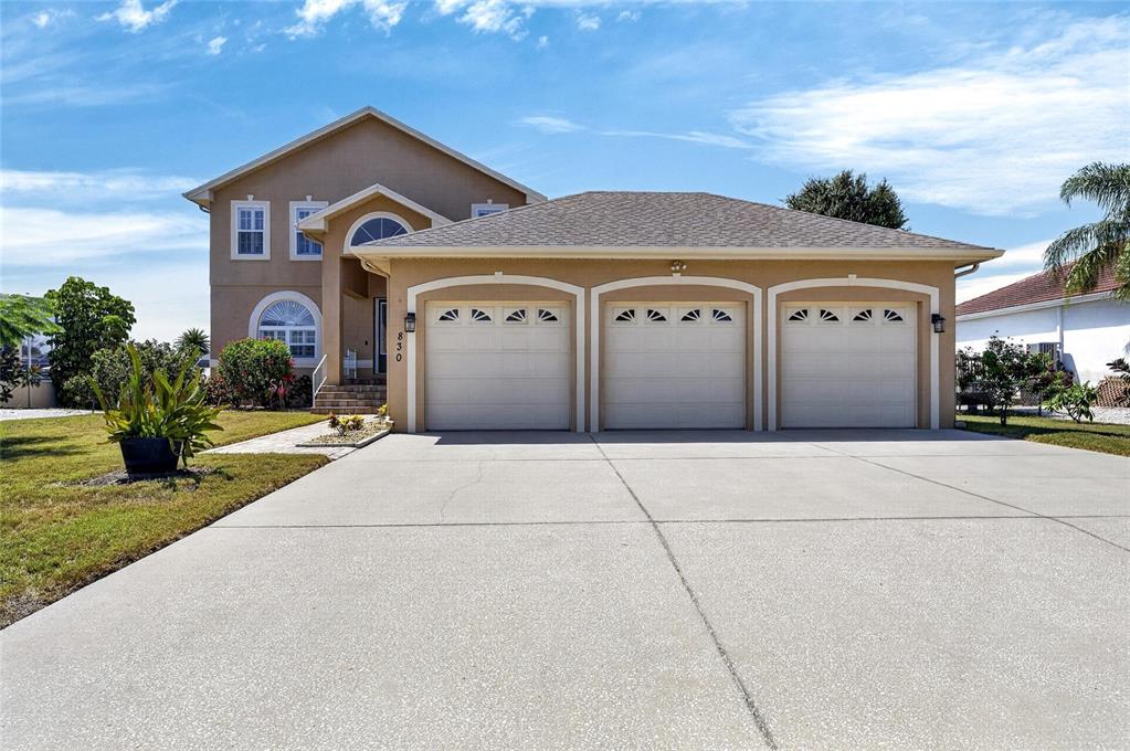 A two-story house with a three-car garage and a concrete driveway under a blue sky — 830 GOLF ISLAND DRIVE, APOLLO BEACH, FL