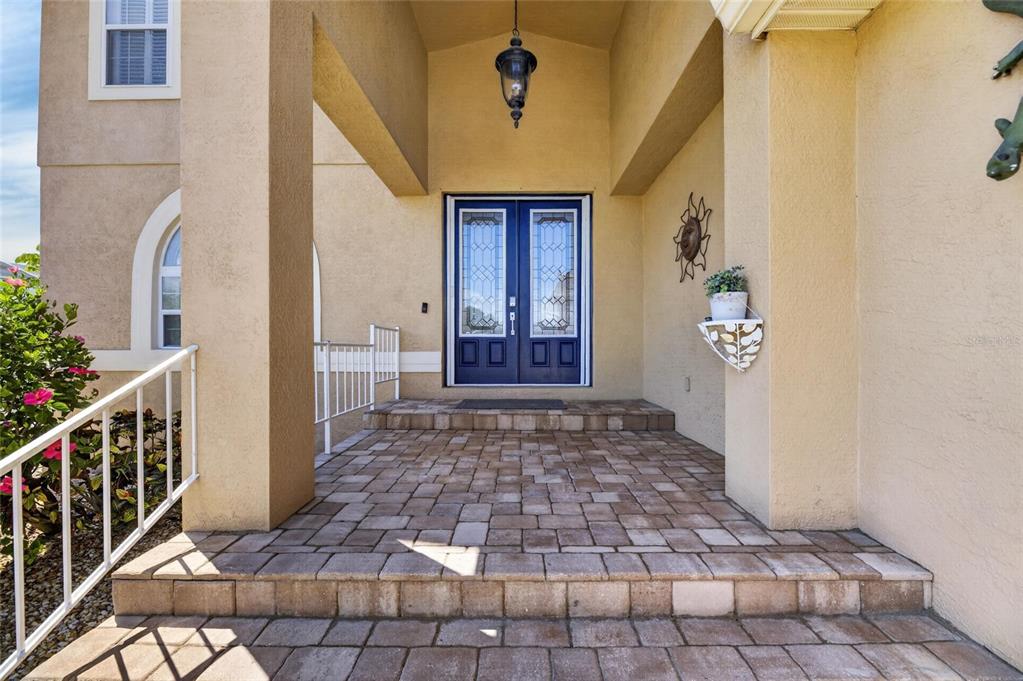 A paved front porch leads to a dark blue double door with glass inserts — 830 GOLF ISLAND DRIVE, APOLLO BEACH, FL