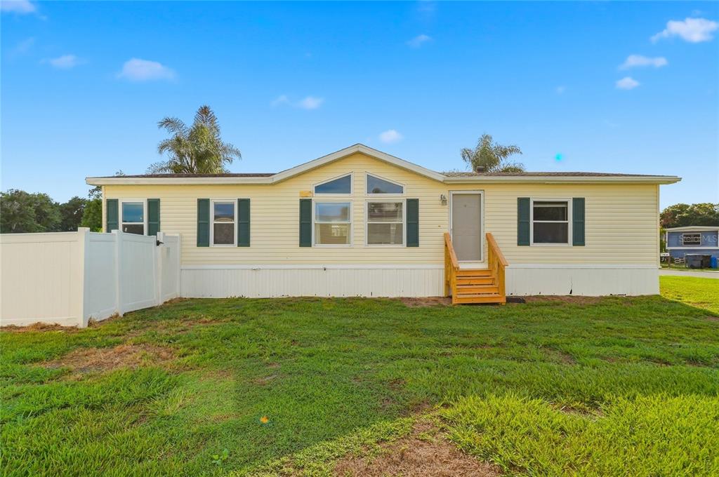 A yellow manufactured home with a gabled roof stands against a vibrant sunset sky — 338 1ST AVENUE N, LAKE WALES, FL