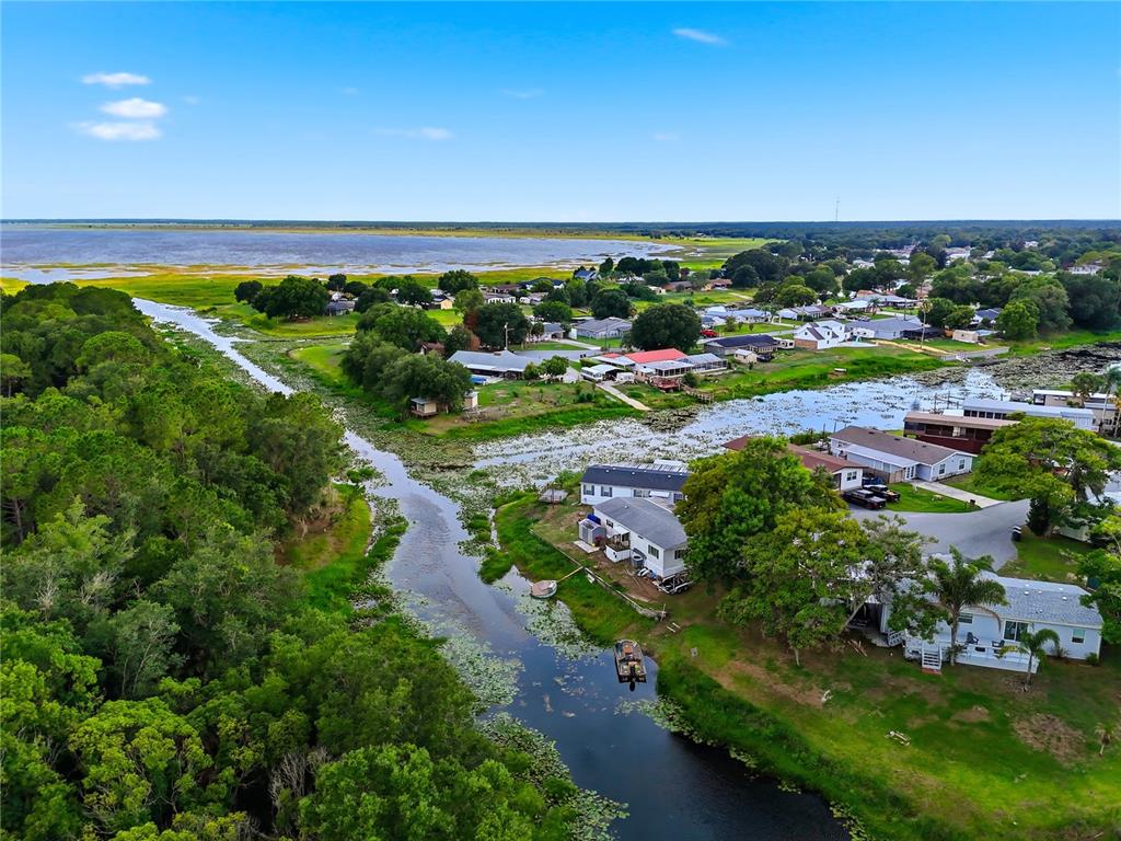An aerial view shows a single-story house with a driveway, shed, and backyard pond — 338 1ST AVENUE N, LAKE WALES, FL