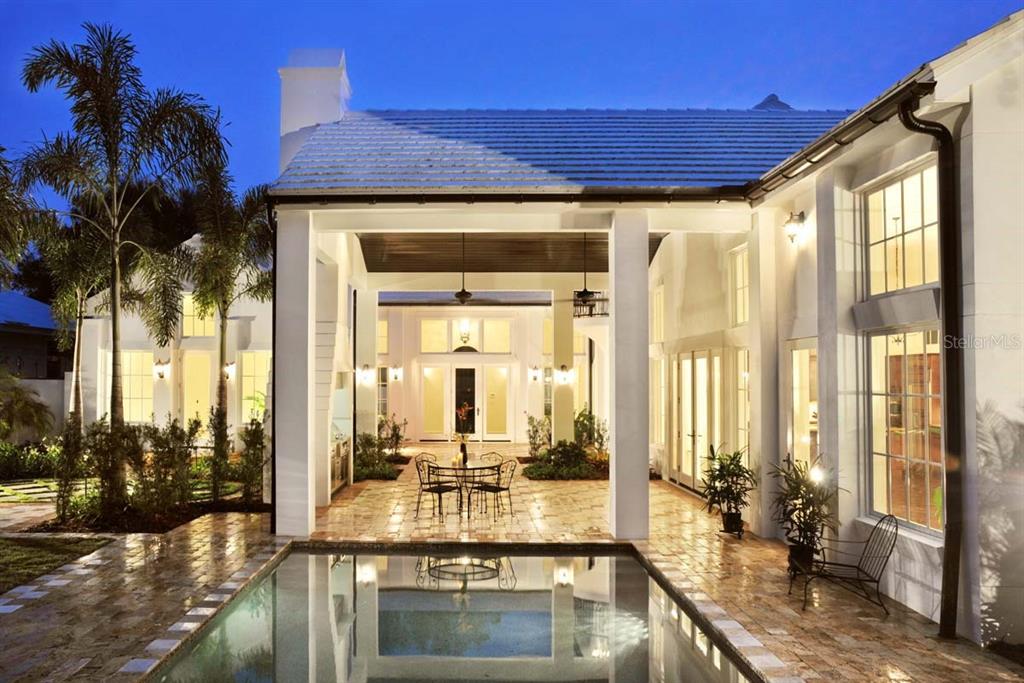 A covered patio with a dining set overlooks a swimming pool at a white house — 1740 S ORANGE AVENUE, SARASOTA, FL