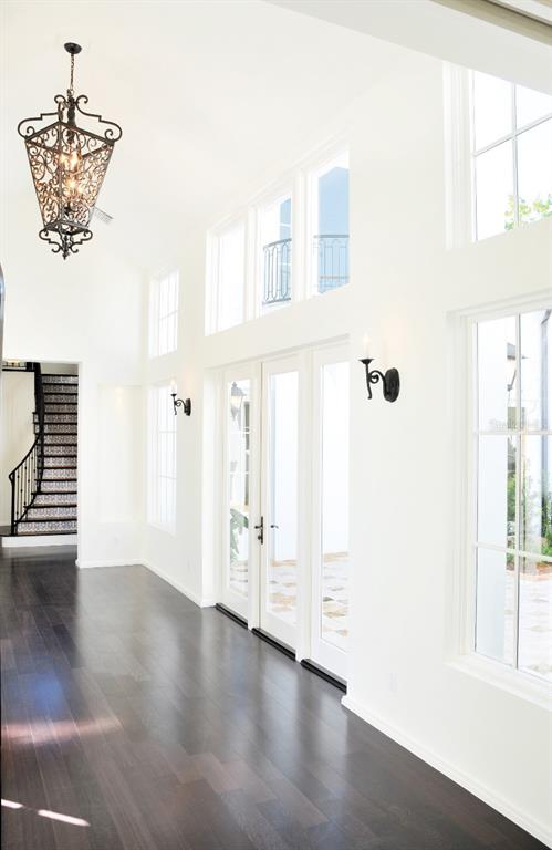 A bright hallway features dark hardwood floors, white walls, a decorative chandelier, and glass doors — 1740 S ORANGE AVENUE, SARASOTA, FL