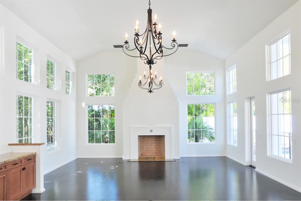 A spacious living room features a tall fireplace, dark wood floors, and a large chandelier — 1740 S ORANGE AVENUE, SARASOTA, FL