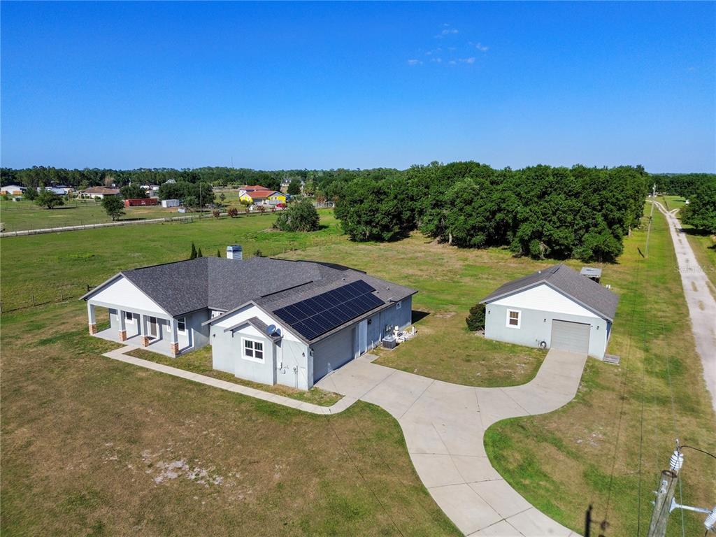 An aerial view shows a house with solar panels, a detached garage, and a driveway — 14805 US-301 N, PARRISH, FL