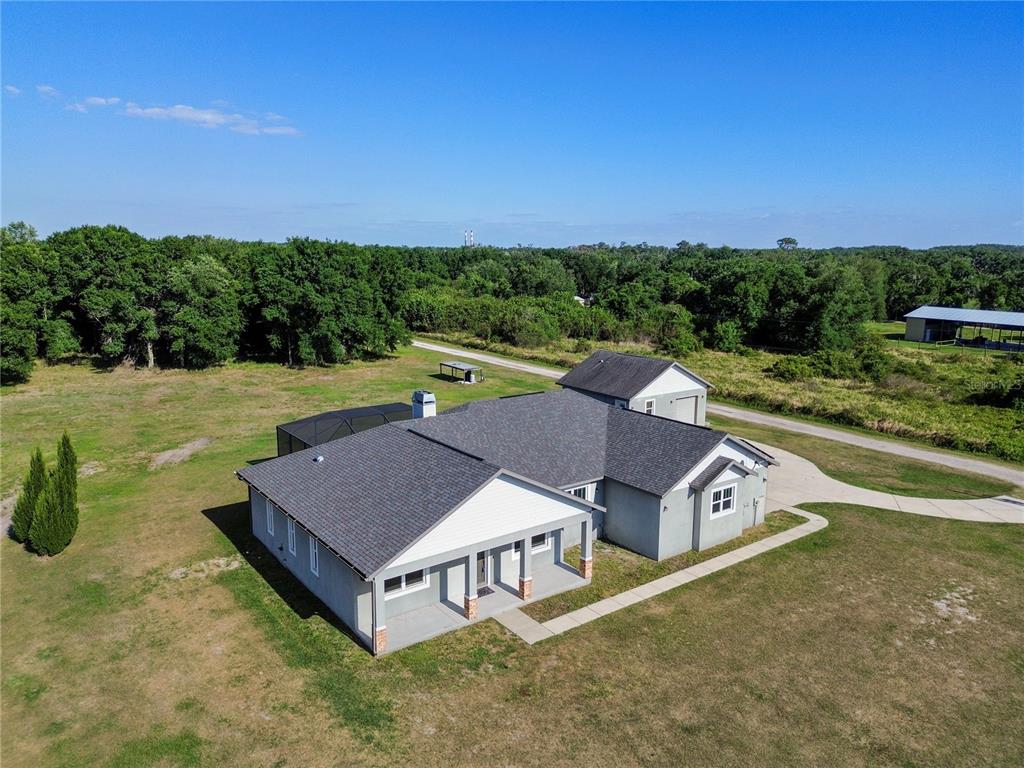 An aerial view shows a gray house with a dark roof, a pool enclosure, and a detached garage — 14805 US-301 N, PARRISH, FL
