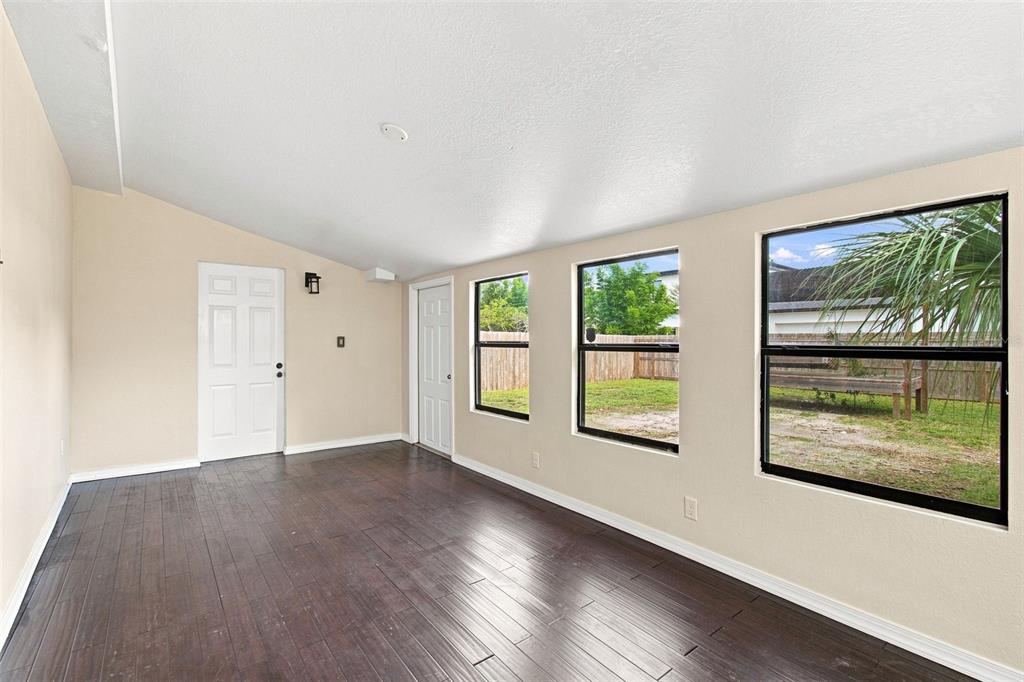 A sunroom features dark wood-look flooring, beige walls, two white doors, and three large windows — 805 W BRADDOCK STREET UNIT A, TAMPA, FL
