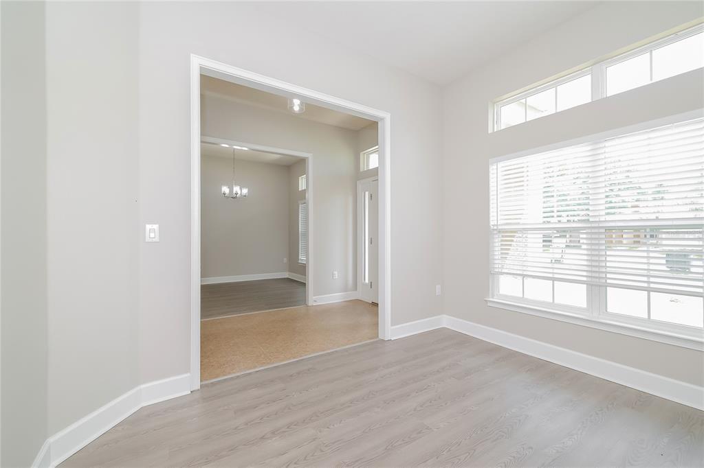 An empty room with light wood-look flooring, white walls, and large windows with blinds — 345 CIMARRON COURT, POINCIANA, FL
